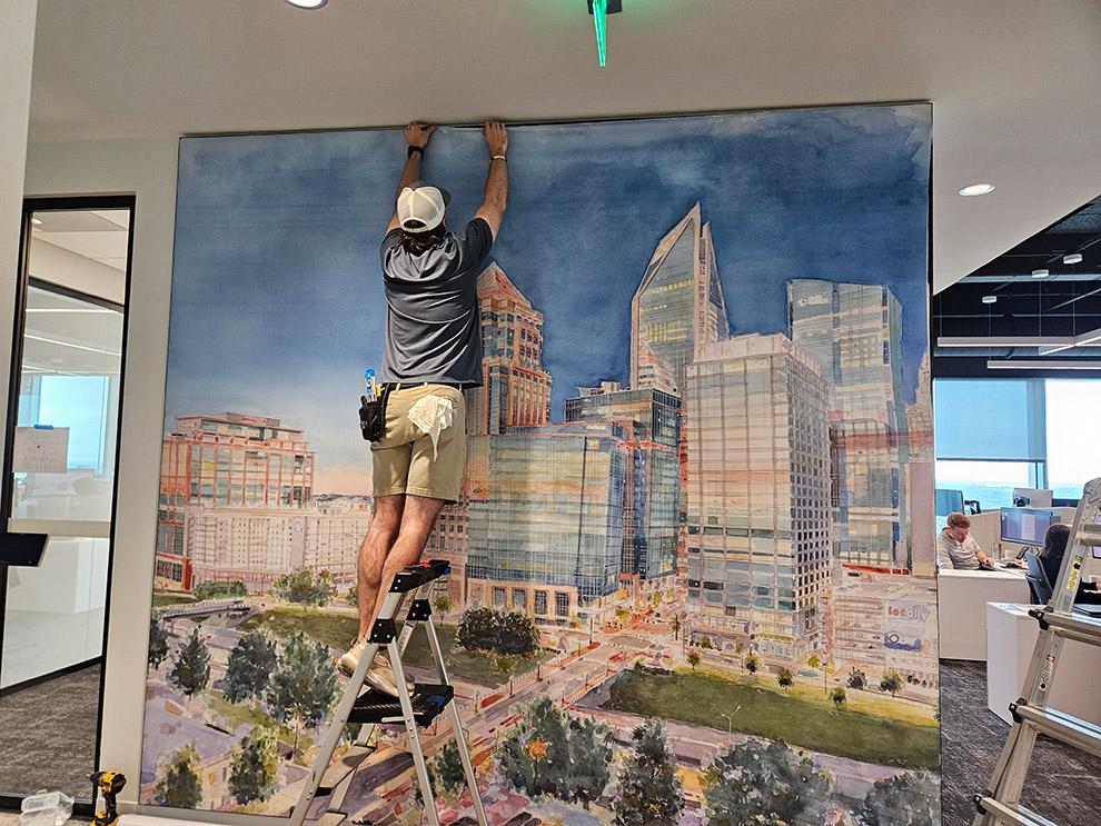 Installer positioning a cityscape mural on an interior wall