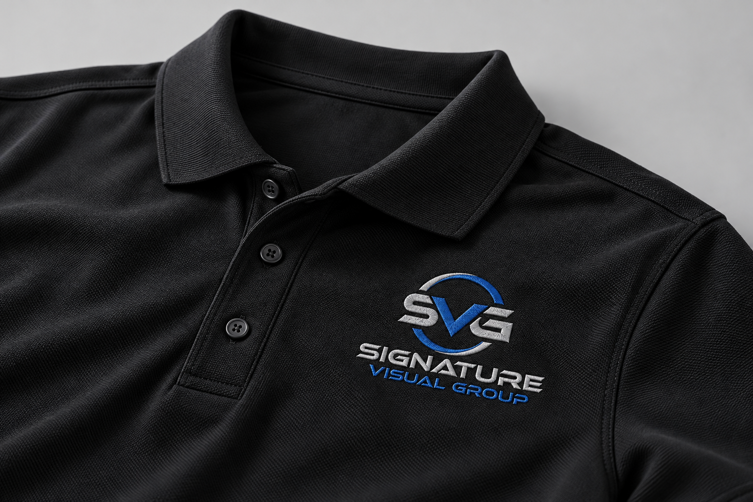 Product mockup of a black polo with embroidered Signature Visual Group logo
